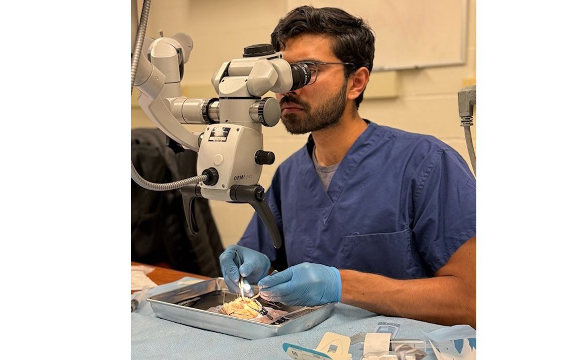 Ophthalmology resident looking at a microscope in a lab
